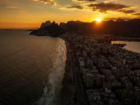 Aerial view of Ipanema and Leblon beaches at sunset with golden light on the ocean, urban buildings, and mountains in Rio de Janeiro, State of Rio de Janeiro, Brazil.