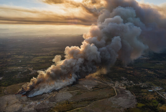 Aerial view of the massive fire at Vertedero Duquesa landfill with thick smoke billowing into the sky at sunset in Pantoja, Santo Domingo, Dominican Republic.