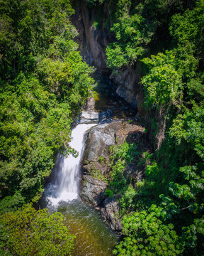 Aerial view of Jima Falls cascading down rocky cliffs surrounded by lush tropical rainforest and dense green foliage in Bonao, Monsenor Nouel, Dominican Republic.