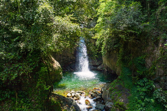 Aerial view of Jima Falls cascading into a turquoise pool surrounded by lush tropical rainforest and dense vegetation, Bonao, Monsenor Nouel Provin, Dominican Republic.