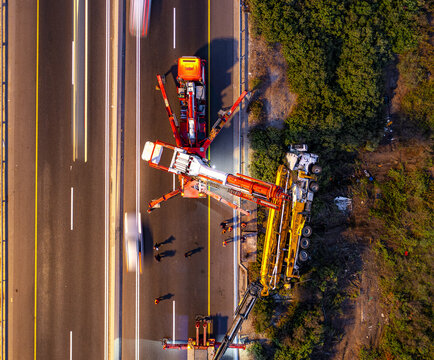 Aerial view of an overturned truck on the side of a highway with emergency response vehicles and personnel on site in Rosh Haayin, Center District, Israel.