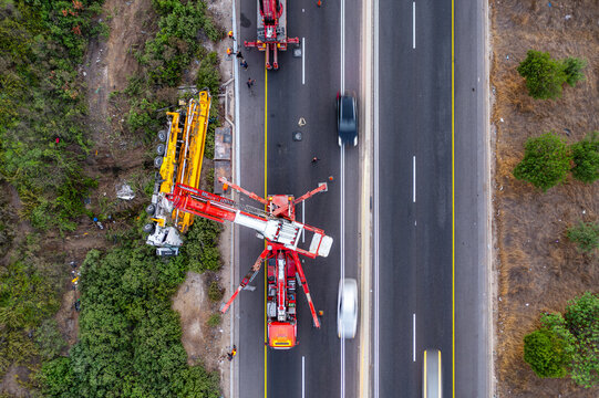 Aerial view of an overturned yellow construction truck on the side of a highway with recovery vehicles and traffic in Rosh Haayin, Center District, Israel.