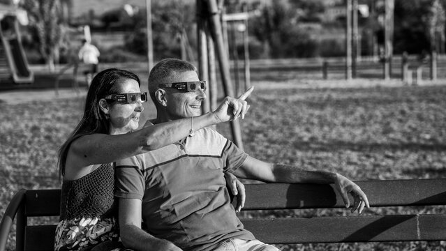 Monochrome image of family watching solar eclipse in peaceful park setting