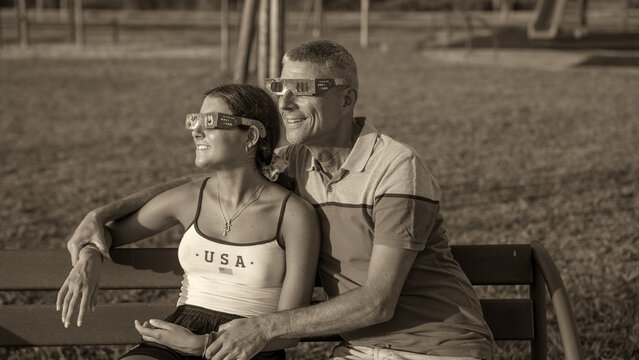 Family enjoying rare solar eclipse event in park with monochrome photography