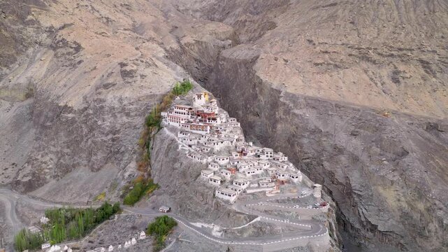 Aerial view of Diskit Monastery perched on a rocky cliffside in the Nubra Valley, surrounded by rugged mountains and a winding road in Diskit, Ladakh, India.