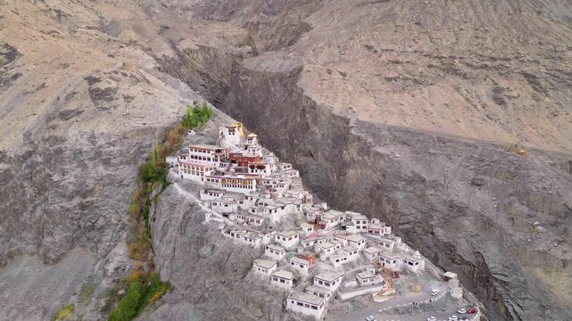 Aerial view of Diskit Monastery perched on a rocky cliff with white buildings and a winding road in the mountainous landscape of Diskit, Ladakh, INDIA.