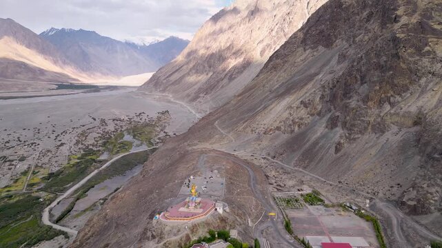Aerial view of the Maitreya Buddha statue at Diskit Monastery, set against the dramatic mountain landscape of the Nubra Valley in Diskit, Ladakh, India.