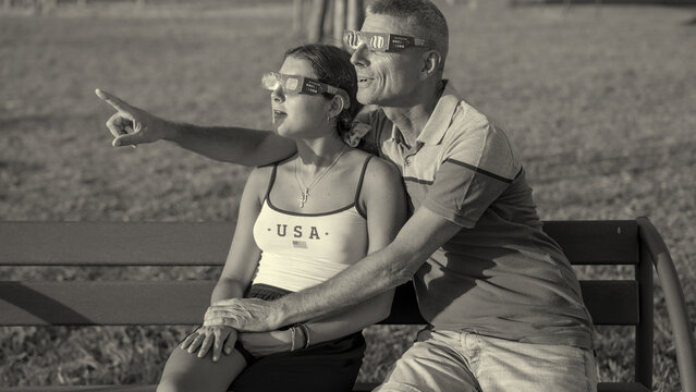 Monochrome image of family watching solar eclipse in peaceful park setting