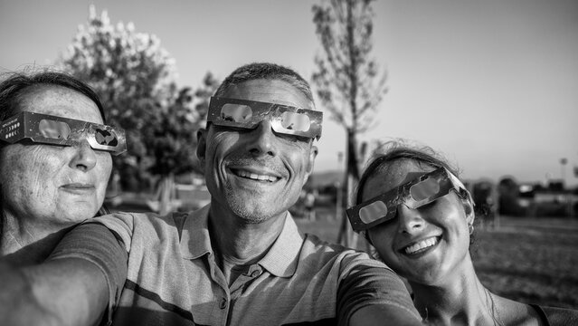 Artistic black and white view of solar eclipse with family in park