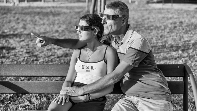 Black and white family silhouette during solar eclipse in natural park landscape