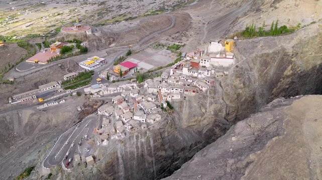 Aerial view of Diskit Monastery perched on a rocky cliffside with traditional white buildings and winding roads in Diskit, Ladakh, India.