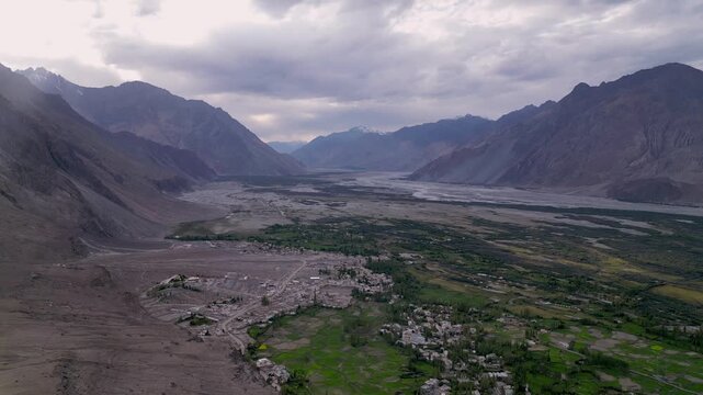 Aerial view of Diskit Monastery nestled in the rugged landscape of the Nubra Valley with green fields and mountain ranges surrounding the village of Diskit, Ladakh, India.