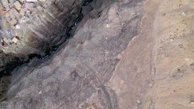 Aerial view of the rugged, arid terrain surrounding Diskit Monastery, featuring rocky slopes and deep ravines in the high altitude desert landscape in Diskit, Ladakh, India.