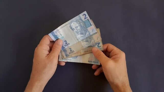 Hands counting Brazilian real banknotes in motion video clip sequence