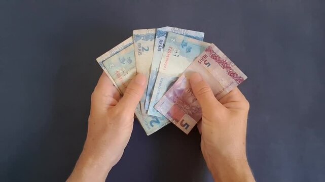 Hands counting Brazilian real banknotes in motion video clip overhead view