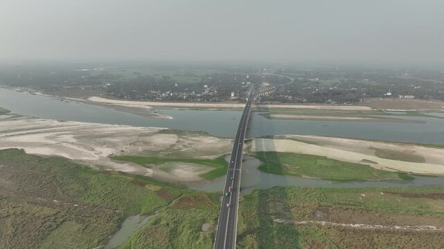 Aerial view of the long bridge spanning across the wide river with sandbanks and green riverbanks in Mawa, Dhaka Division, Bangladesh.