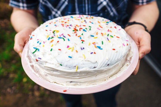 Young man holding birthday cake with sprinkles in a plaid shirt