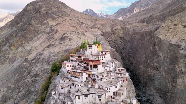Aerial view of Diskit Monastery perched on a rocky cliffside with traditional white buildings and prayer flags in Diskit, Ladakh, India.