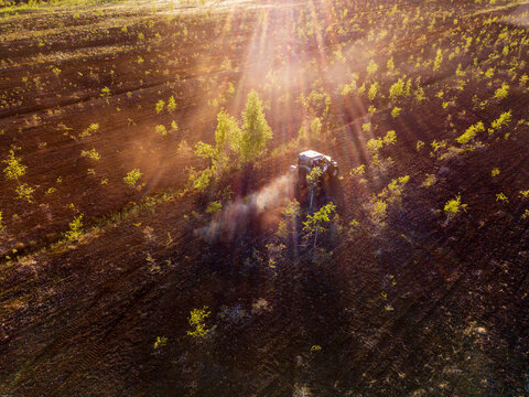 Aerial view of an off-road vehicle driving through a field at golden hour with dust kicking up in Sortavala, Respublika Kareliya, Russia.