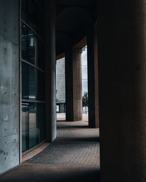 View of modern architectural columns and arches forming a walkway with glass panels and tiled flooring in Vancouver, British Columbia, Canada.