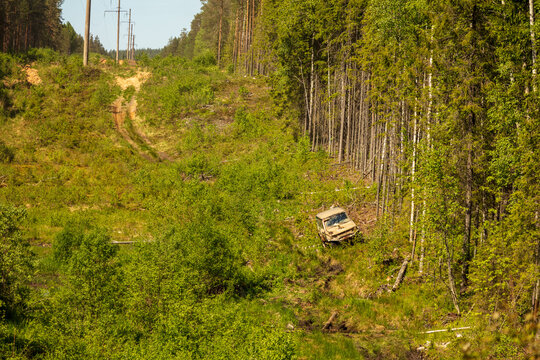 View of an off-road vehicle navigating a muddy forest track beneath power lines in the lush wilderness near Lake Ladoga, Sortavala, Respublika Kareliya, Russia.