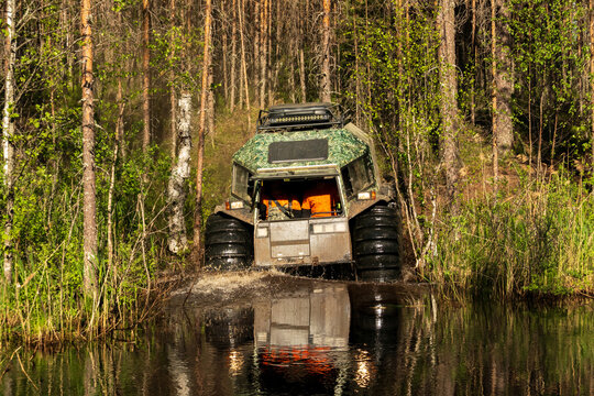 View of an all-terrain vehicle driving through a muddy water crossing in the forest near Lake Ladoga in Sortavala, Respublika Kareliya, Russia.
