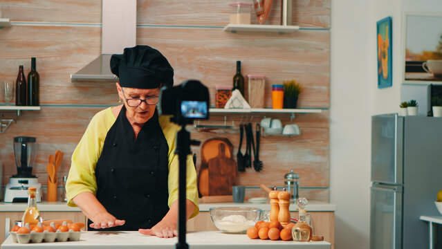 Experienced chef demonstrates pastry preparation on camera while sharing culinary knowledge with viewers at home, inside a practical home kitchen for digital recipe viewers.