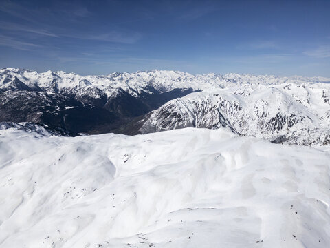 Aerial view of the snow-covered peaks of the Baqueira ski resort under a clear blue sky in the Pyrenees mountains, Baqueira, Cataluna, Spain.