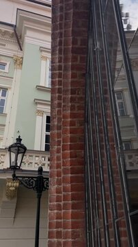 subtle upward view reveals historic neoclassical facade with pale green plaster, gold accented capitals, multi pane sash windows and glass reflections in city light