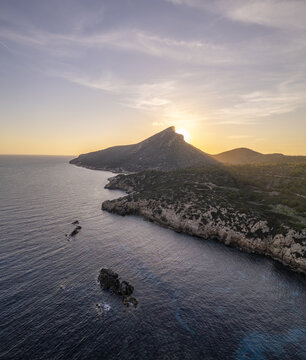 Aerial view of Port de Sa Dragonera at sunset with rocky cliffs and calm sea in Islas Baleares, Spain.