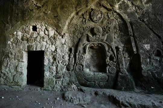View of ancient stone carvings and a dark cave entrance in Mallorca, Balearic Islands, Spain.