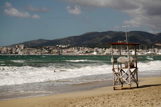 View of a lifeguard tower on the beach in Mallorca with the city skyline and mountains in the background in Balearic Islands, Spain.