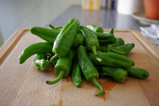 Fresh pimientos de padron green peppers on wooden cutting board