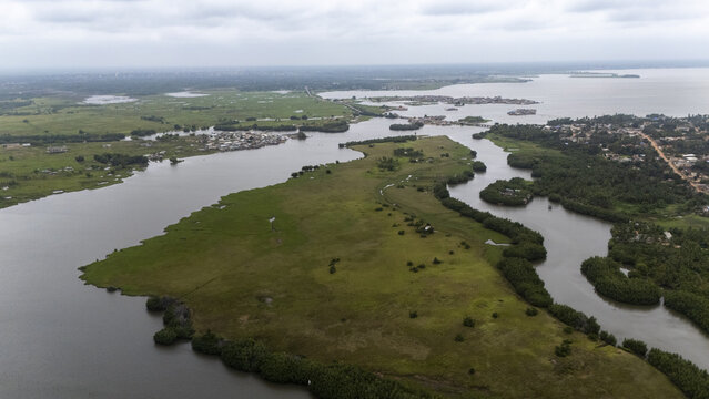 Aerial view of the Gogotinkpon area featuring lush green wetlands, winding river channels, and scattered rural settlements under a cloudy sky in Kpomasse, Mono, Benin.