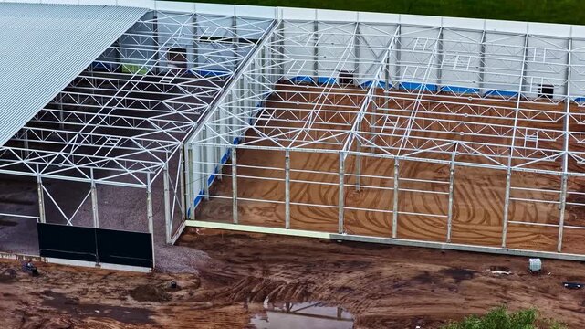 Aerial view of a large steel frame structure under construction on a dirt lot in Jelgava, Jelgava pilseta, Latvia.