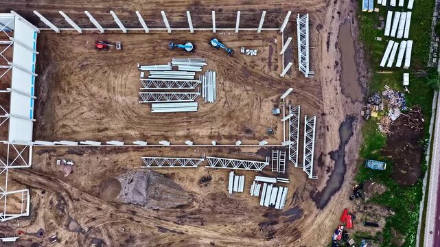 Aerial view of construction site with steel beams and concrete pillars on muddy ground in Jelgava, Jelgava pilseta, Latvia.