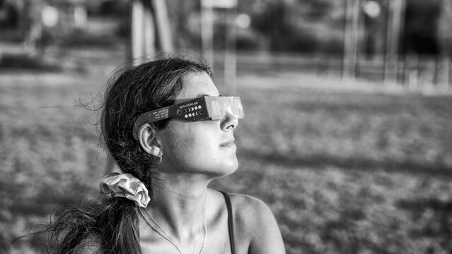 Black and white image of child watching solar eclipse in natural setting