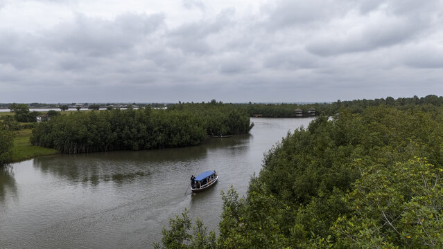 Aerial view of a boat navigating the river through the dense mangroves of Gogotinkpon in Kpomasse, Mono, Benin.