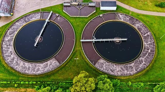 Aerial view of circular wastewater treatment tanks with aeration systems surrounded by green grass in Jelgava, Jelgava City, Latvia.