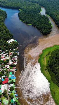 Aerial view of Parque Nacional Tortuguero with boats on the river and the town of Roxana along the bank in Roxana, Limon Province, Costa Rica.