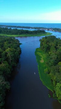 Aerial view of Parque Nacional Tortuguero featuring a winding river flowing through dense tropical rainforest towards the Caribbean Sea in Roxana, Limon Province, Costa Rica.