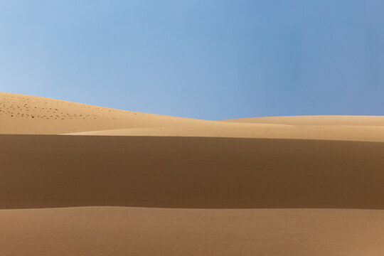 View of golden sand dunes under a clear blue sky in Da'ira, Socotra, Yemen.
