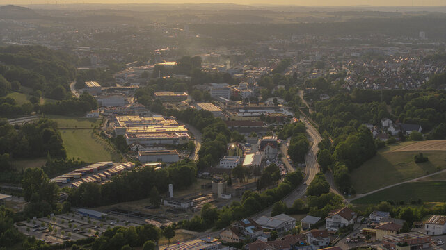 Aalen, Germany - 13 July 2026: Aerial view of Papierfabrik Palm GmbH and Co. KG industrial facility surrounded by lush green forests and residential areas in the golden hour light.
