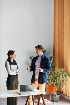 Business professionals discussing work in a modern office, collaborating on a project and sharing ideas during a meeting with a laptop and documents on the table