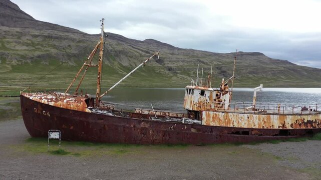 Aerial view of the historic rusted Gardar BA 64 shipwreck resting on the beach with mountains in the background in Saudlauksdalur, Vesturbyggd, Iceland.