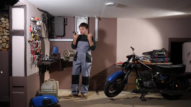 Male mechanic expressing frustration while working on repairing a vintage motorcycle within a cluttered garage workshop, encountering difficulties during the restoration process
