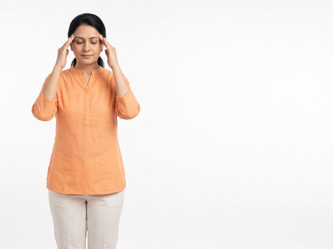 Middle aged Indian housewife with mild headache pressing temples isolated on white background for healthcare wellness insurance and medical advertising