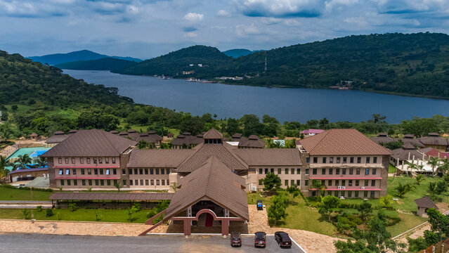 Akosombo, Eastern Region, Ghana - 11 September 2022: Aerial view of The Peninsula Resort on the banks of Lake Volta, featuring large buildings with brown tiled roofs and lush green grounds.