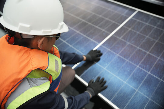 Aerial view of a technician in a high visibility vest and hard hat inspecting solar panels in Berau Regency, East Kalimantan, Indonesia.