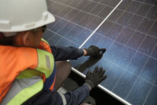 View of a worker in a hard hat and high-visibility vest inspecting solar panels in Berau Regency, East Kalimantan, Indonesia.